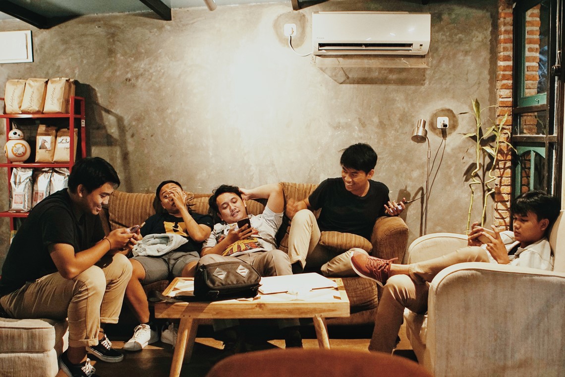 Group of friends sitting in the lounge chatting and being on their phones