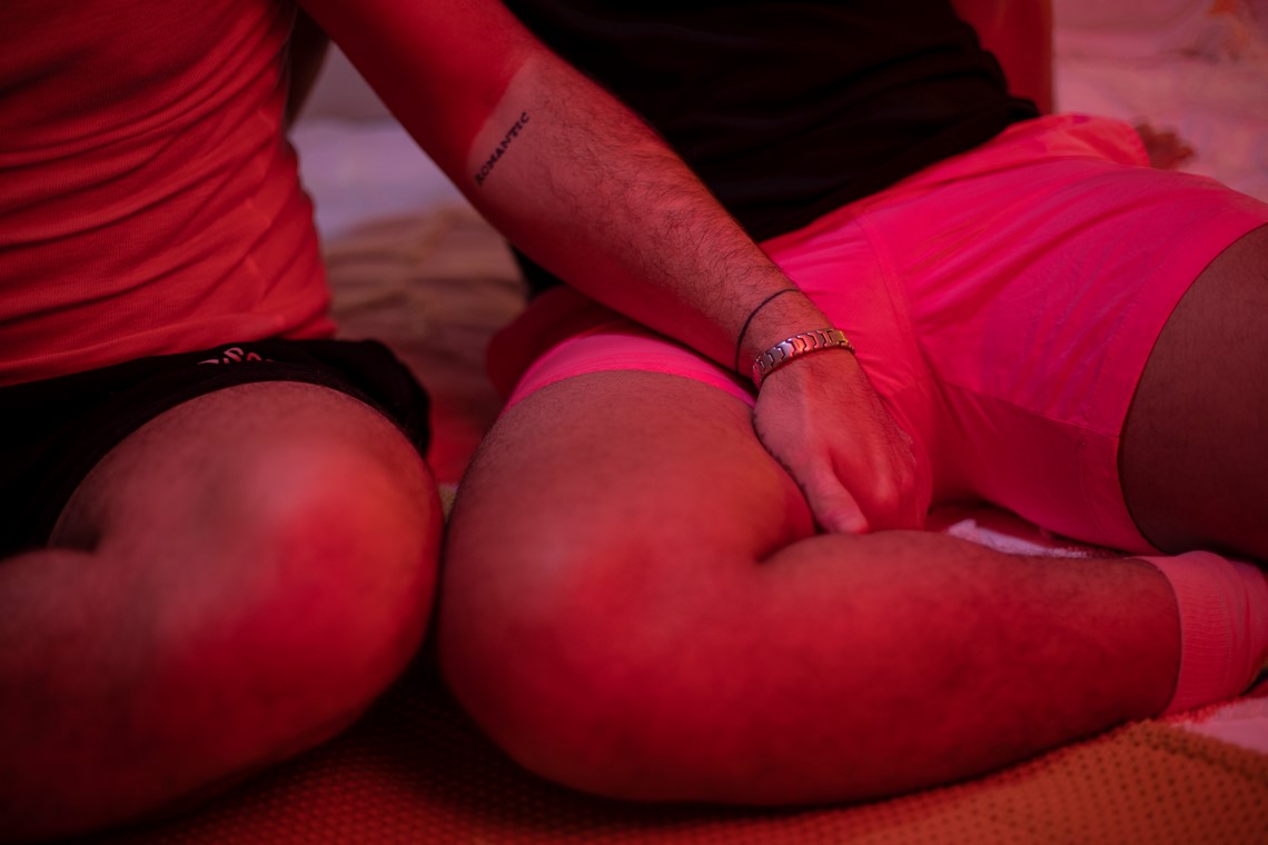 People being intimate on their bed, grabbing their leg
