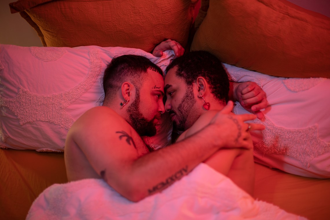 Two gay people cuddling in bed