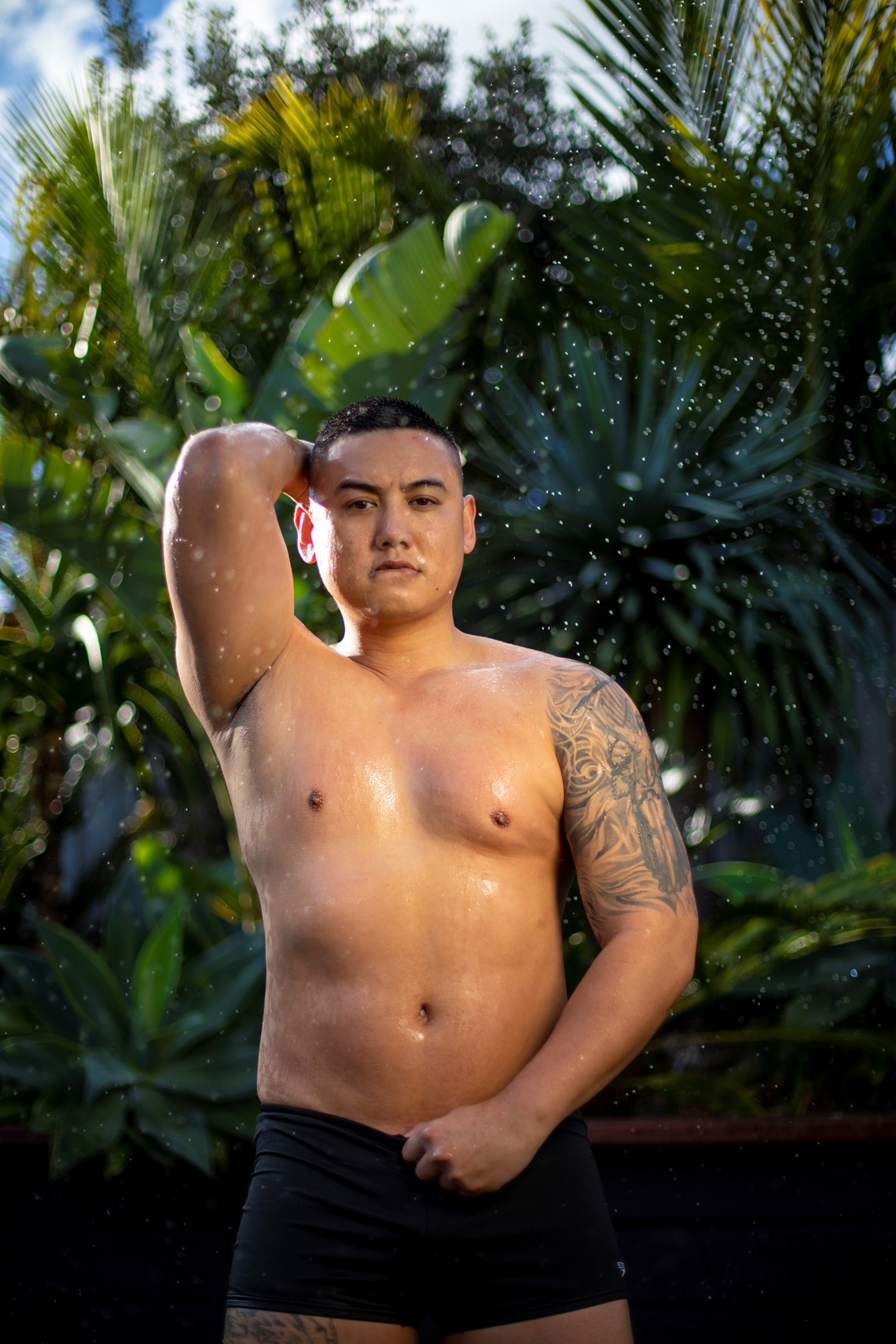 shirtless person outside being splashed with water