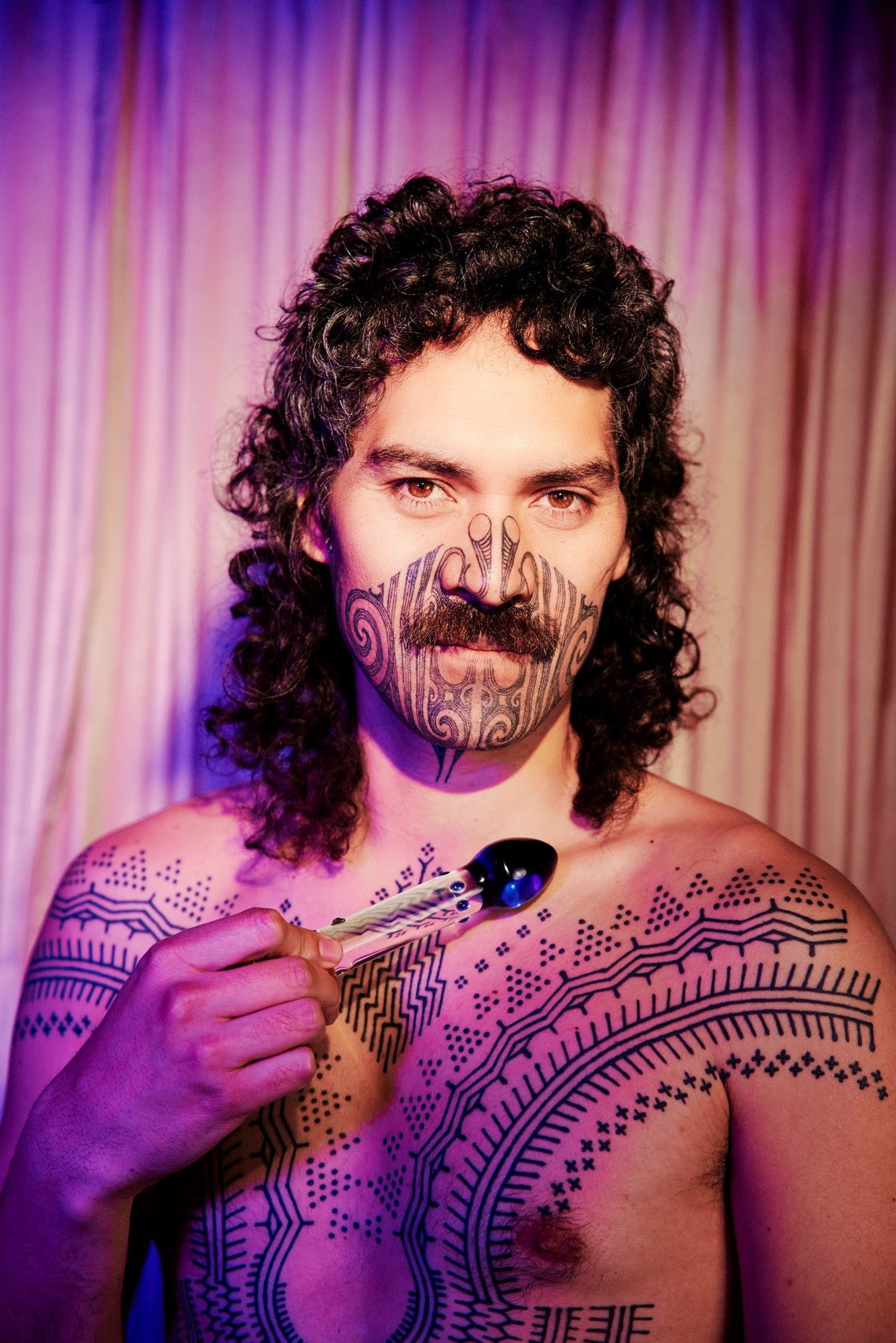 Shirtless person holding a glass dildo