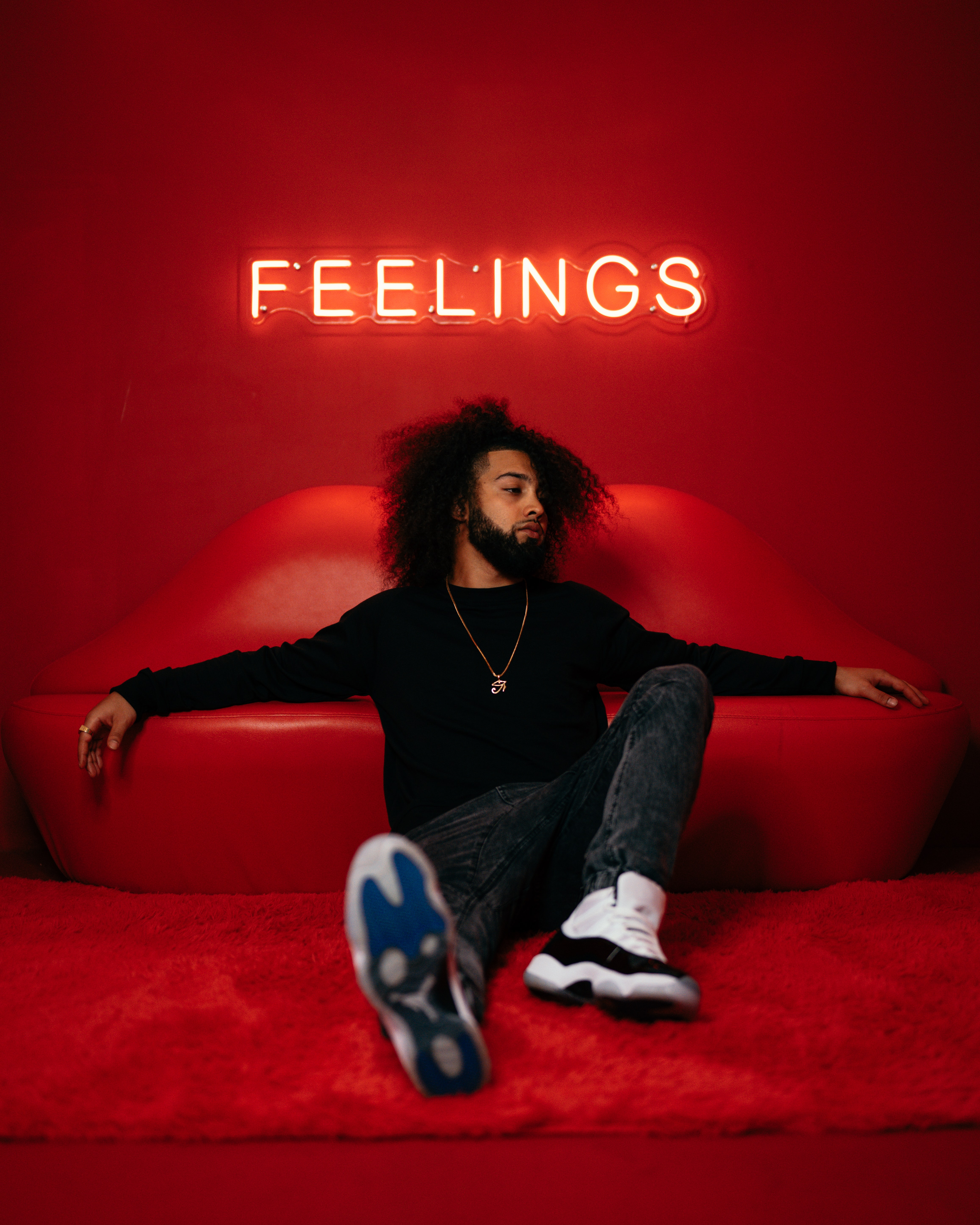 Person sitting in front of a lip shaped couch and neon 'feelings' lights