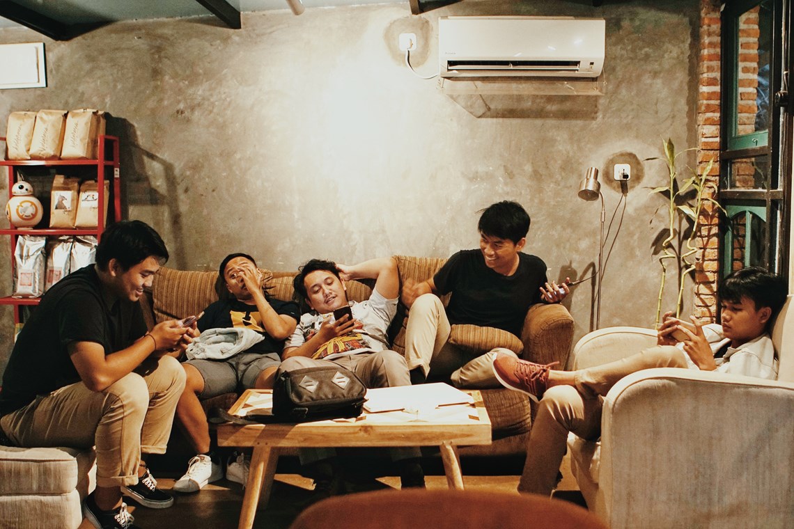 Group of friends sitting in the lounge chatting and being on their phones