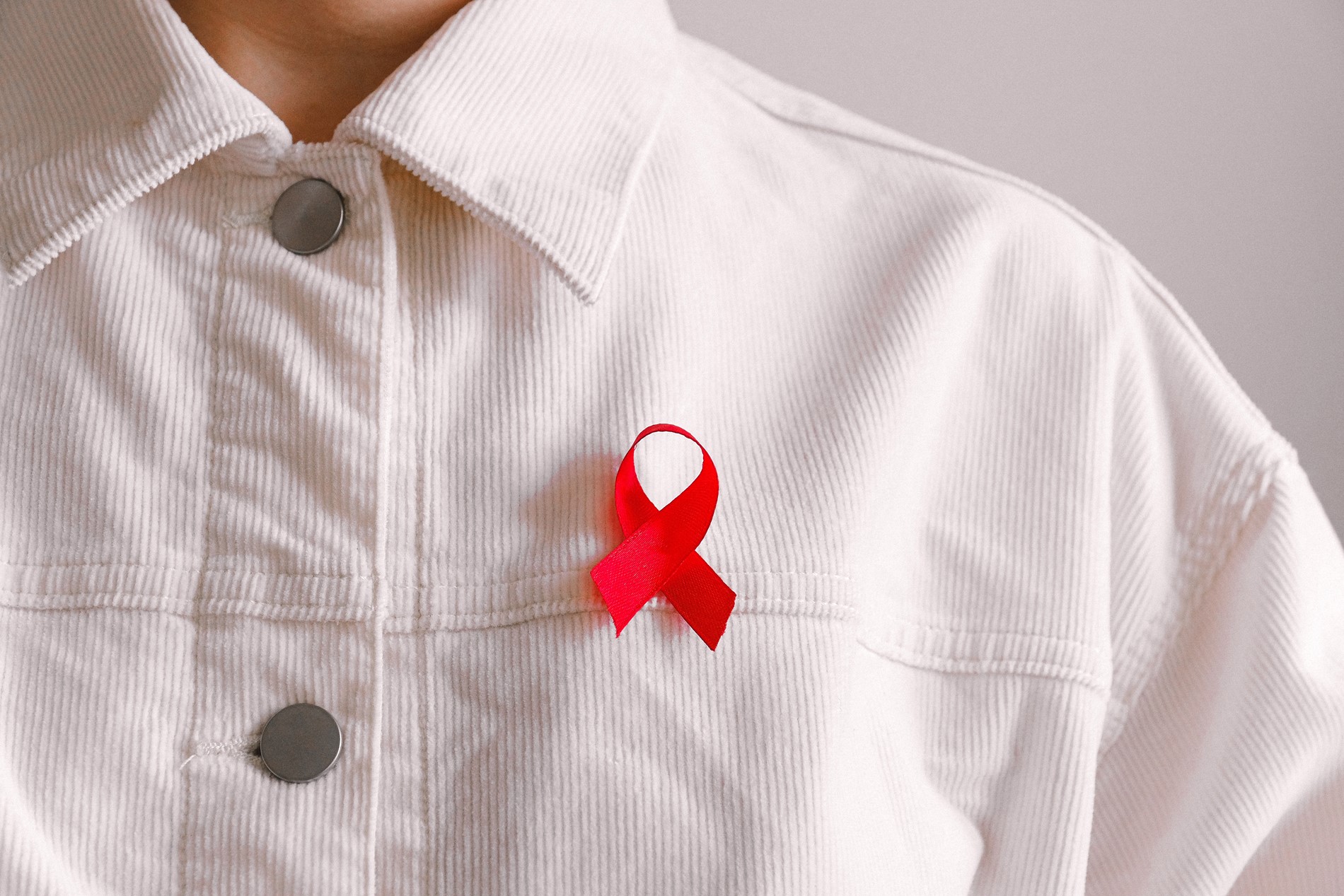 Close up of a red ribbon on someone's shirt.
