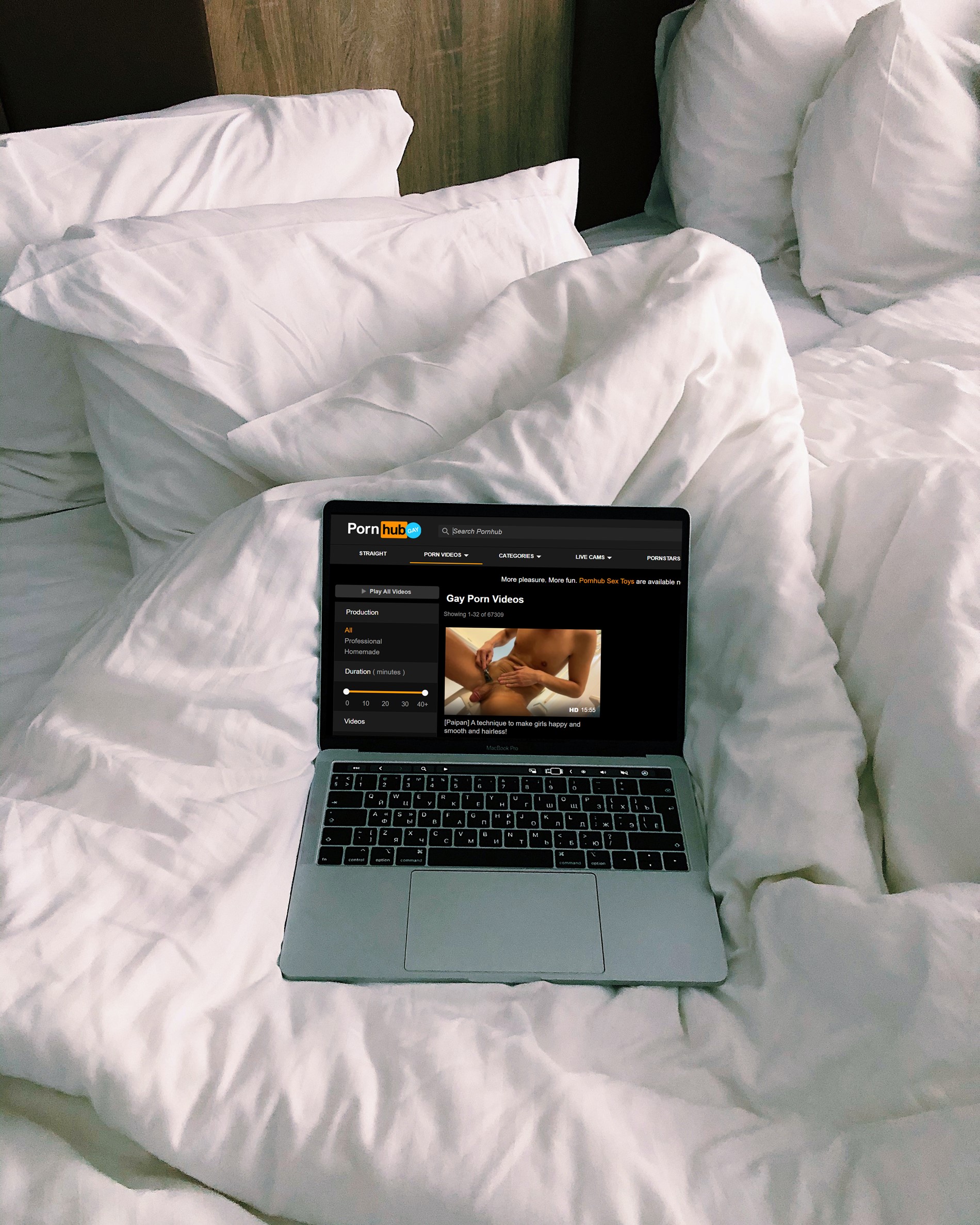 Laptop on a bed displaying gay porn via Porn Hub