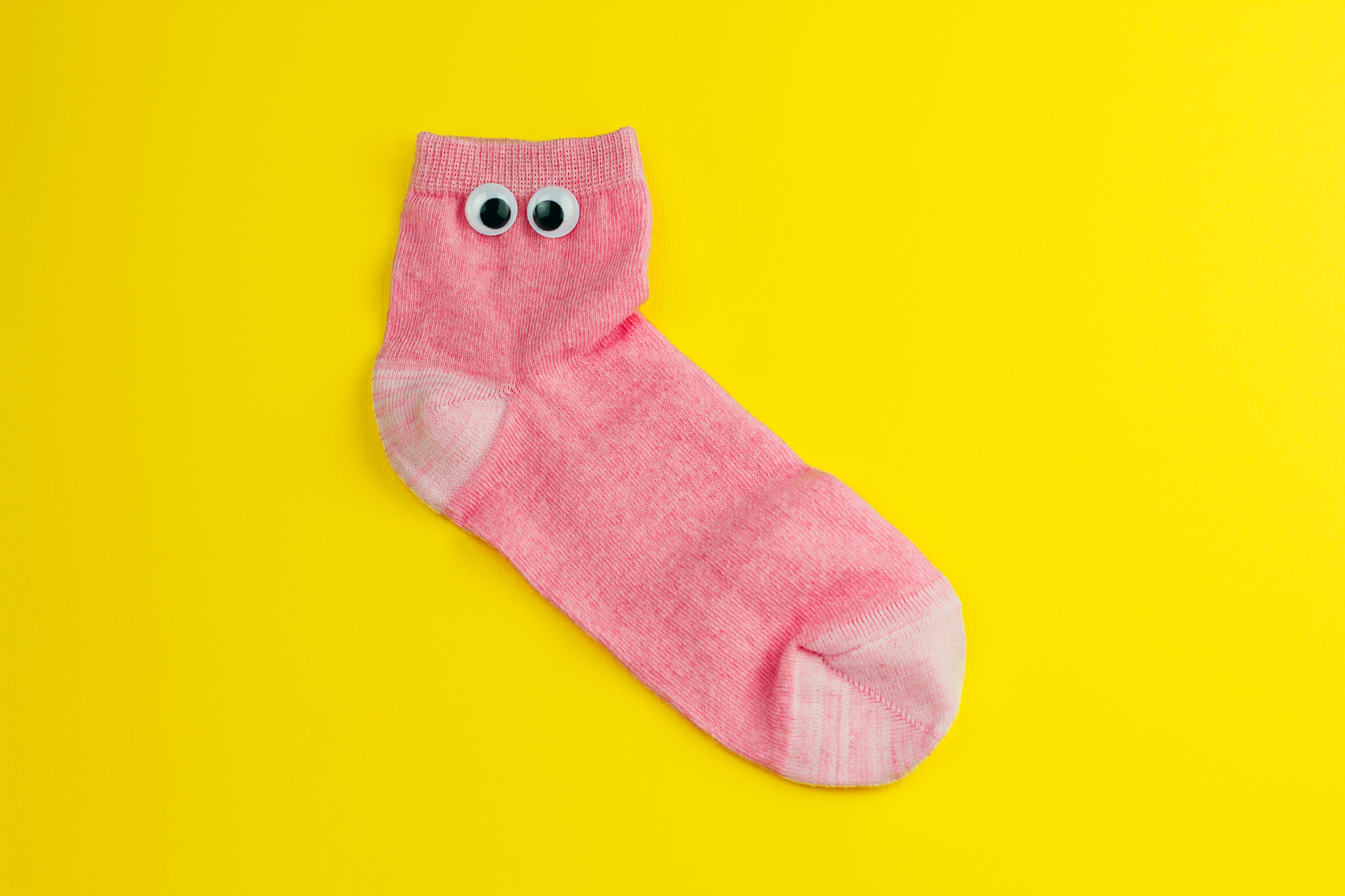 Pink sock with googly eyes with a yellow back ground