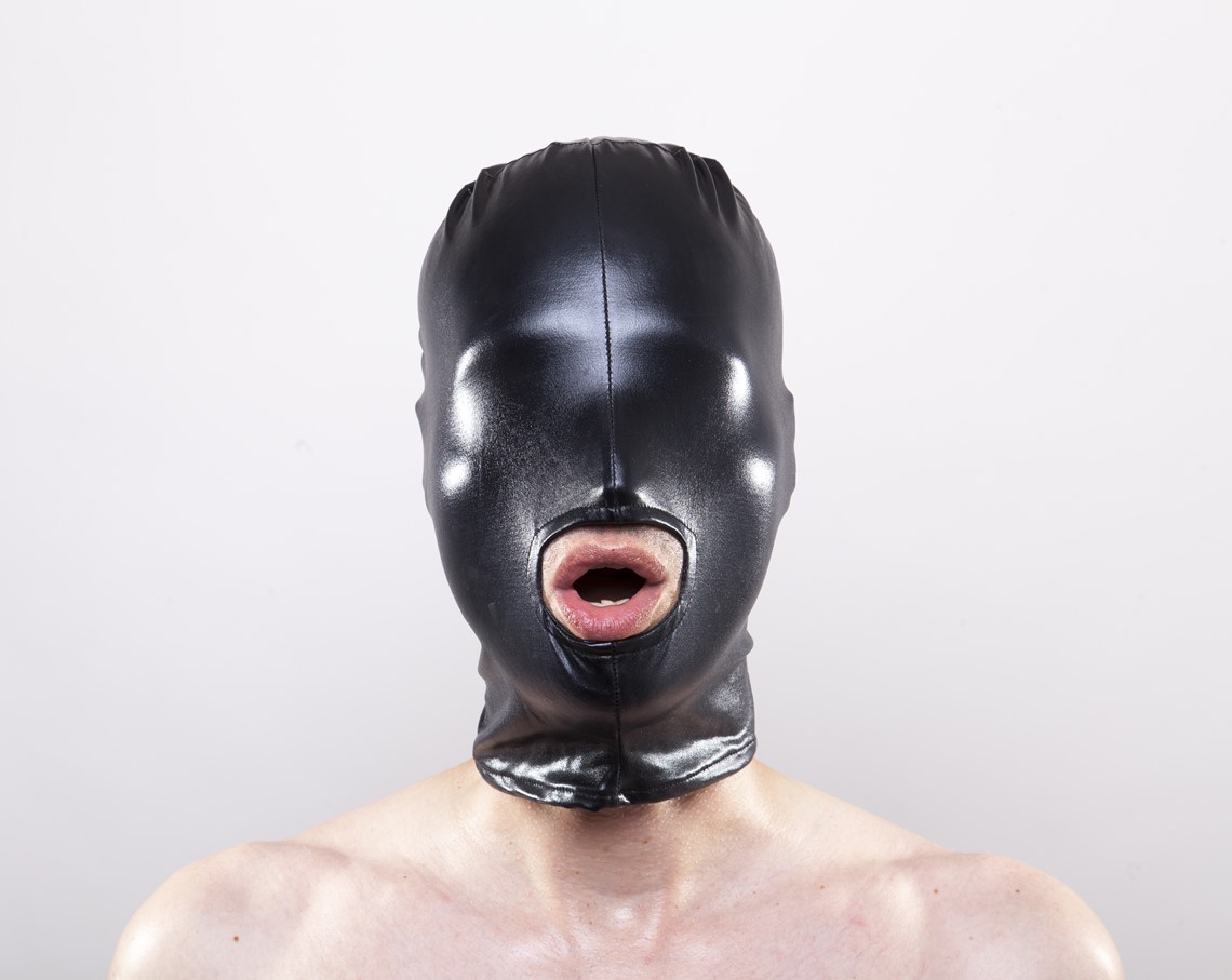 Person partaking in bondage, wearing a black face mask