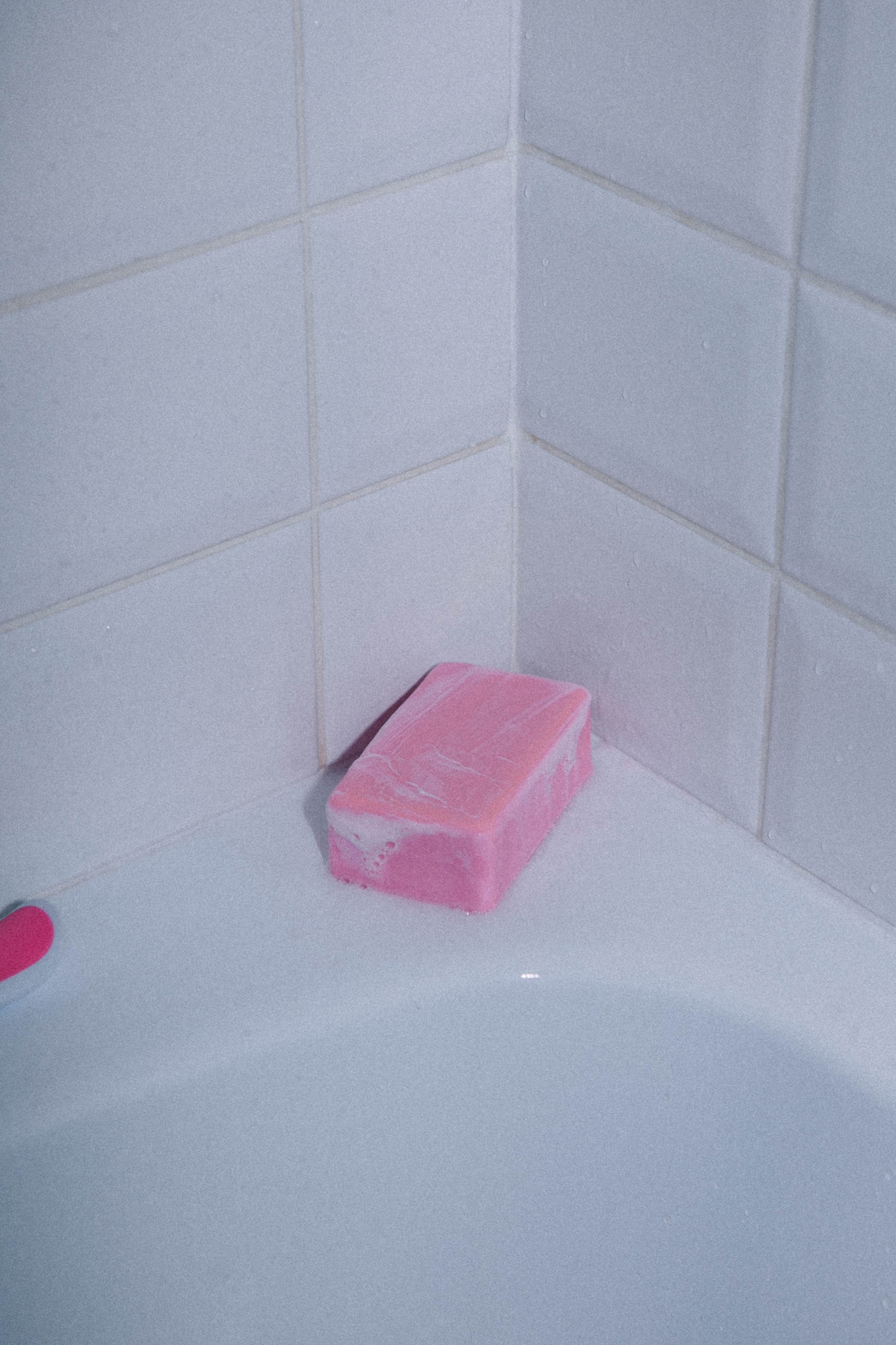 Pink block of soap in the corner of a bathtub