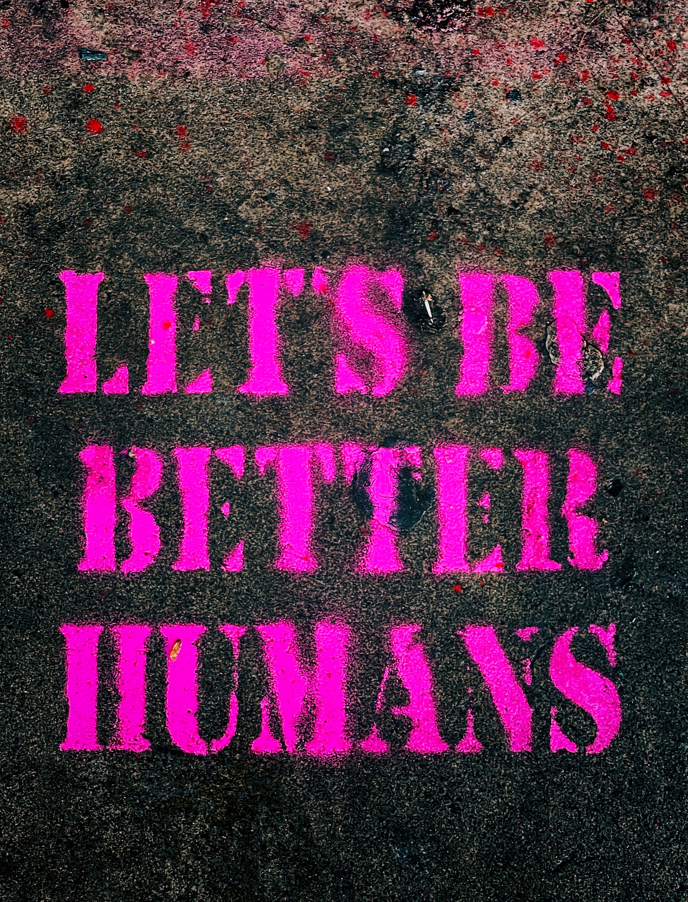 LET'S BE BETTER HUMANS graffitied in pink on the ground