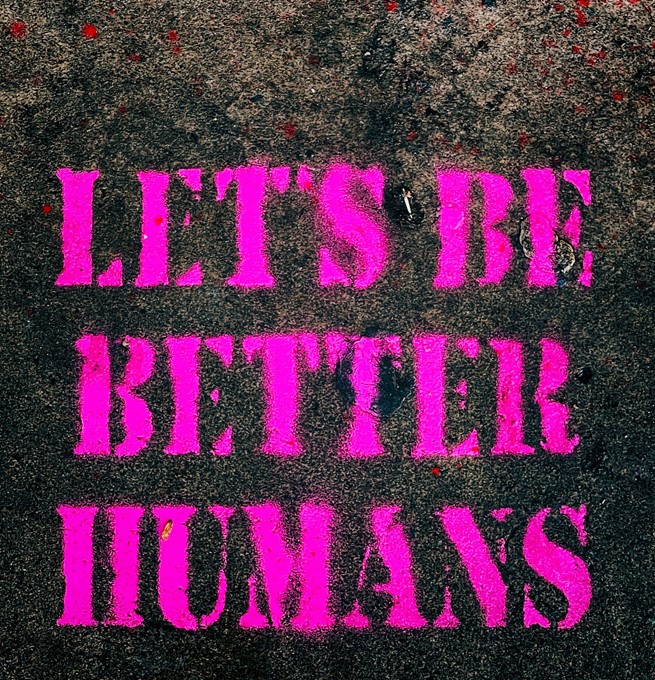 LET'S BE BETTER HUMANS graffitied in pink on the ground