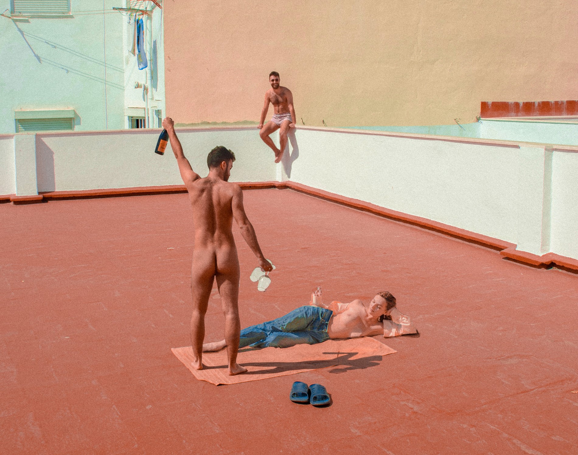 three half naked people drinking alcohol on a roof top