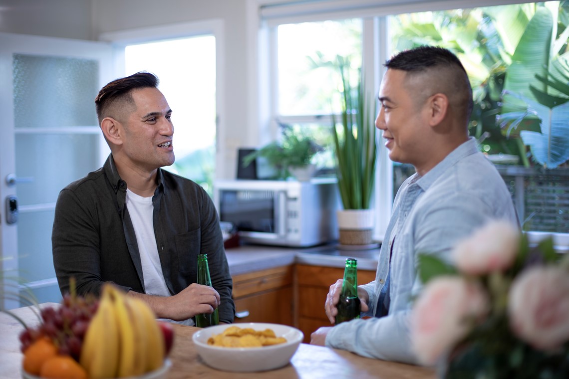 Two people talking on the kitchen with a beer