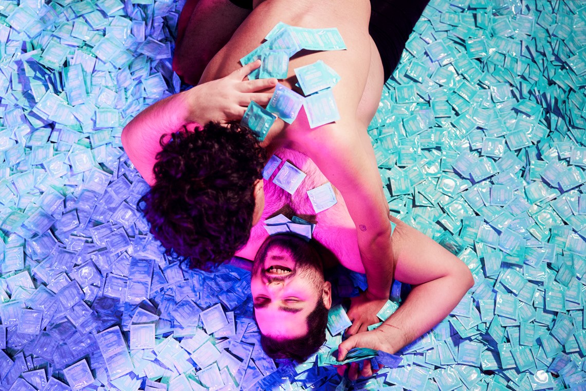 Couple hugging over a pile of condoms